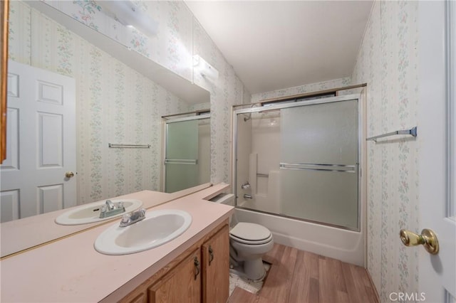 full bathroom with toilet, enclosed tub / shower combo, hardwood / wood-style flooring, and vanity