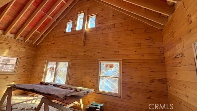 game room featuring beamed ceiling, high vaulted ceiling, and wooden walls