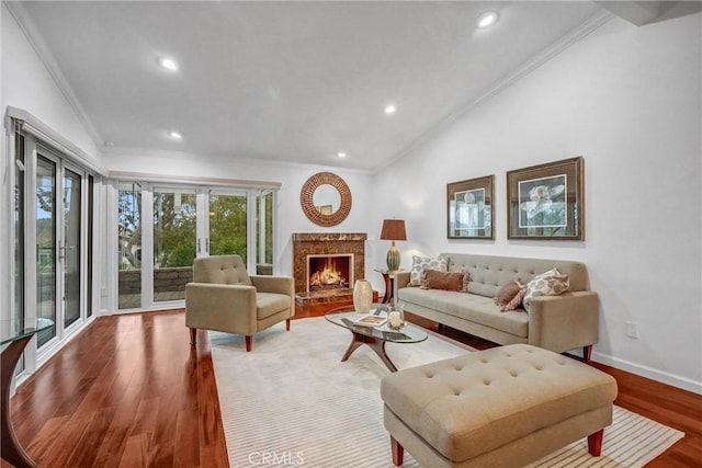 living room with vaulted ceiling, a premium fireplace, ornamental molding, and hardwood / wood-style flooring