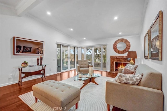 living room featuring hardwood / wood-style flooring, ornamental molding, a premium fireplace, and vaulted ceiling with beams