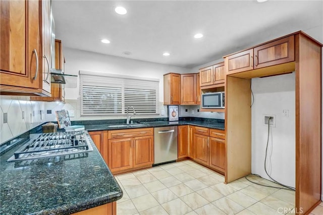 kitchen with tasteful backsplash, sink, appliances with stainless steel finishes, light tile patterned floors, and dark stone counters