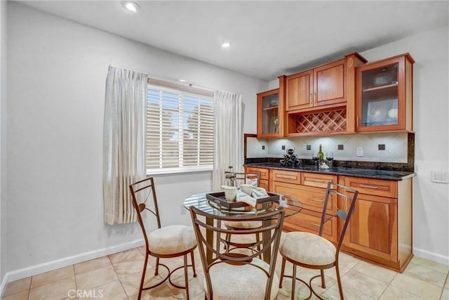 kitchen featuring light tile patterned floors, decorative backsplash, and dark stone countertops