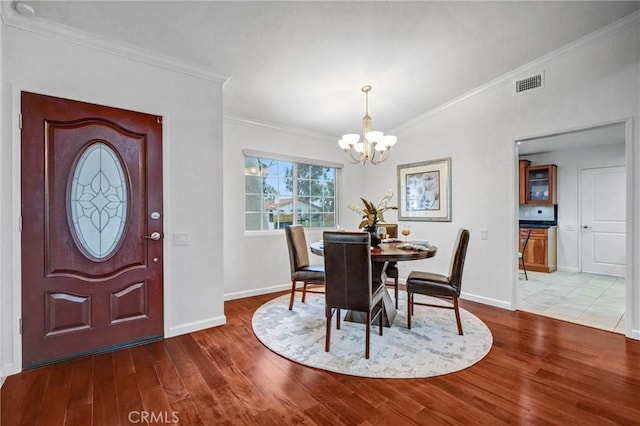 dining space featuring crown molding, a chandelier, and hardwood / wood-style flooring