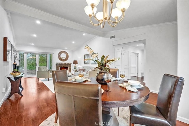 dining space featuring an inviting chandelier, hardwood / wood-style floors, ornamental molding, and vaulted ceiling with beams