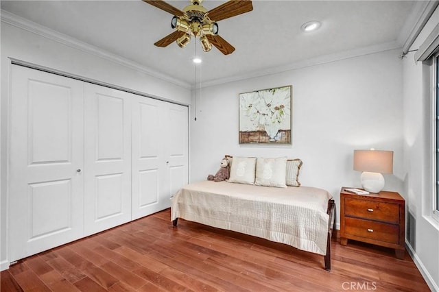 bedroom featuring ceiling fan, hardwood / wood-style floors, a closet, and ornamental molding