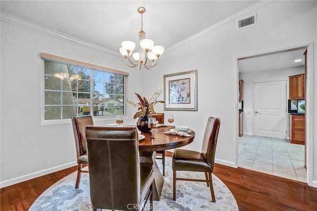 dining space with light hardwood / wood-style flooring, ornamental molding, and a notable chandelier