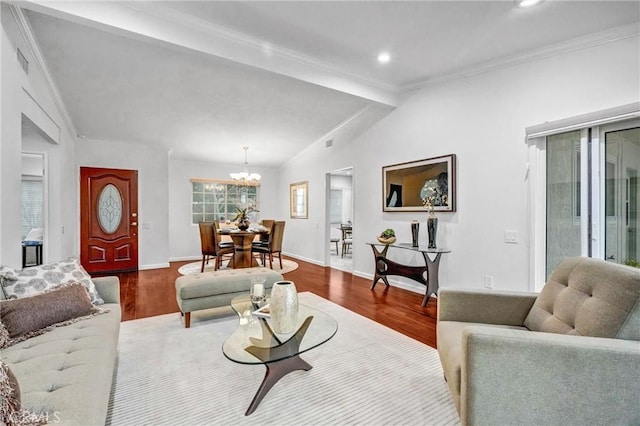 living room featuring vaulted ceiling, crown molding, hardwood / wood-style floors, and a notable chandelier