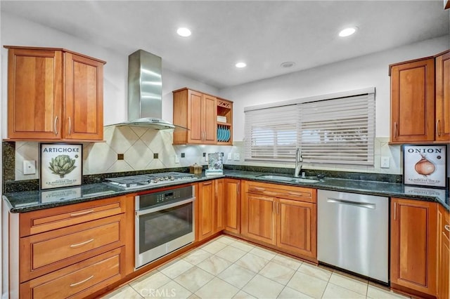 kitchen with wall chimney exhaust hood, stainless steel appliances, dark stone countertops, decorative backsplash, and sink