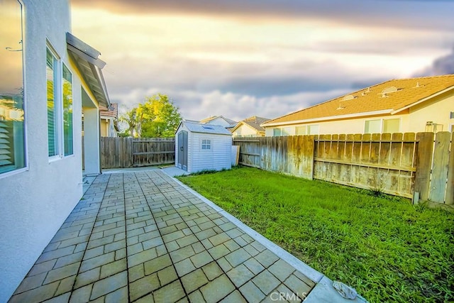 yard at dusk featuring a patio area and a storage unit