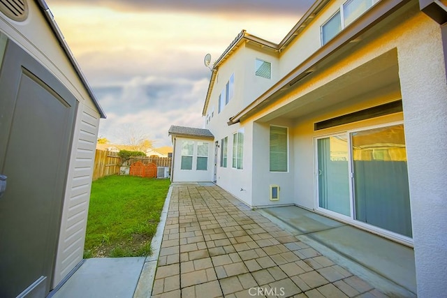 back house at dusk with a patio area and a yard