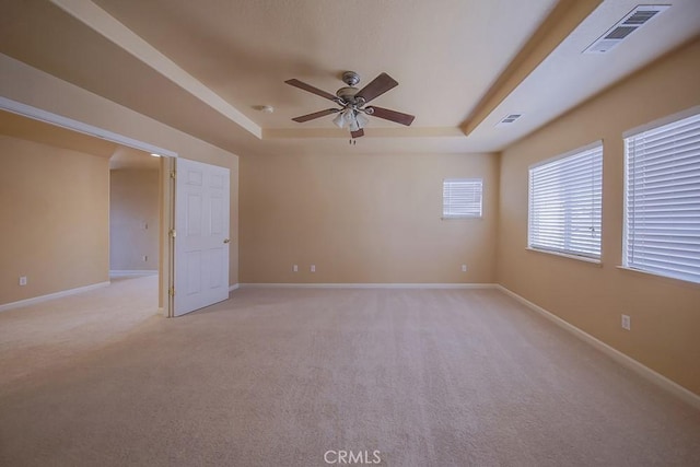 empty room featuring light carpet, ceiling fan, and a tray ceiling