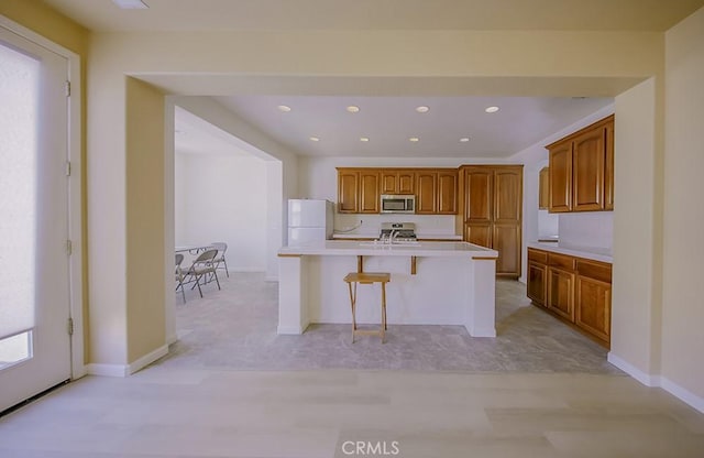 kitchen with stainless steel appliances, a kitchen bar, and a center island with sink