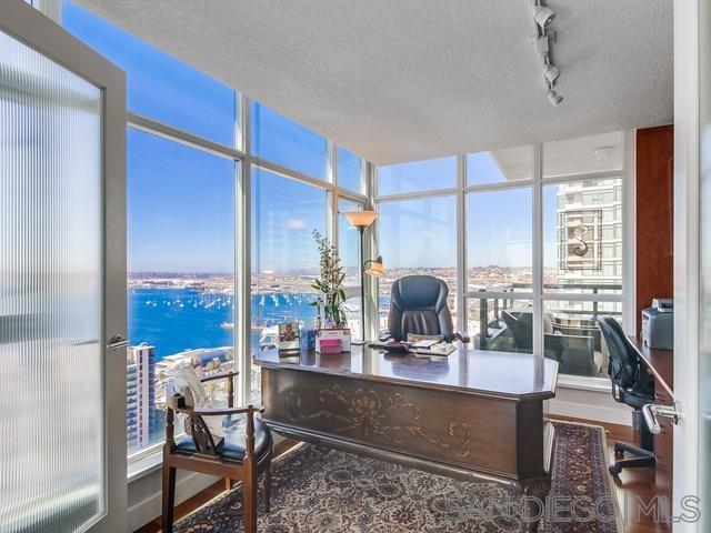 home office with a textured ceiling, track lighting, a water view, and wood-type flooring