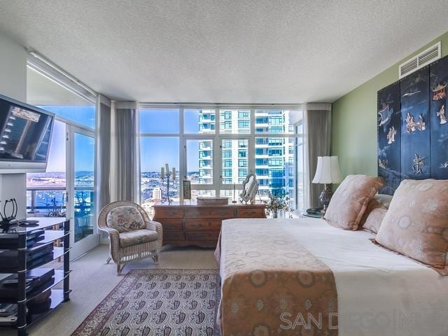 carpeted bedroom with floor to ceiling windows, a textured ceiling, and multiple windows