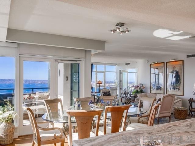 dining space featuring a water view and a textured ceiling