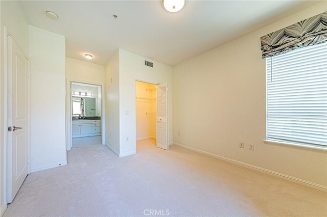 100 S Alameda St Unit 307, Los Angeles, CA 90012 - unfurnished bedroom with light colored carpet, baseboards, ensuite bath, a spacious closet, and a closet