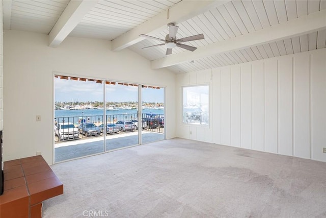 carpeted spare room featuring ceiling fan, lofted ceiling with beams, and a water view