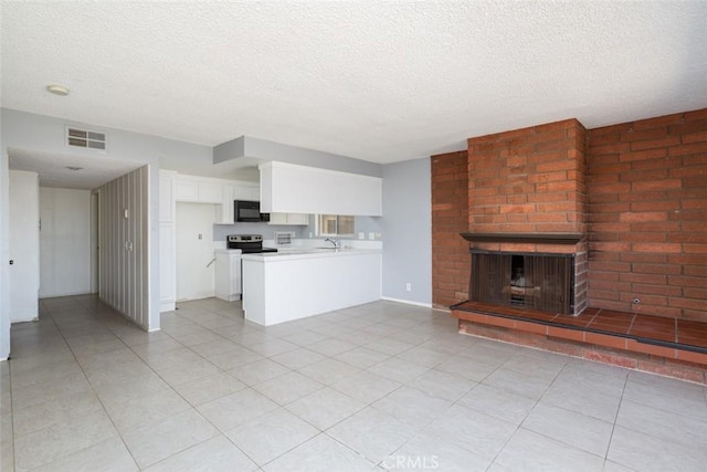 kitchen featuring white cabinetry, kitchen peninsula, a brick fireplace, stainless steel electric range, and sink