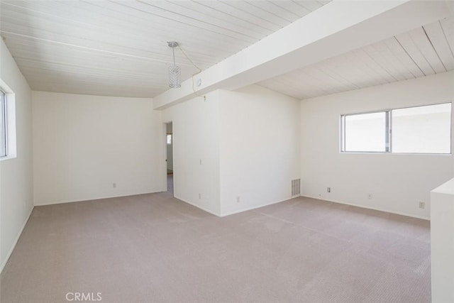 unfurnished room with light carpet, a healthy amount of sunlight, and beamed ceiling