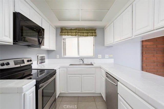 kitchen featuring light tile patterned floors, tile countertops, appliances with stainless steel finishes, white cabinets, and sink