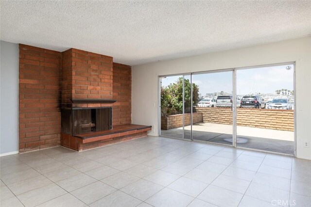 unfurnished living room featuring light tile patterned floors, a brick fireplace, and a textured ceiling