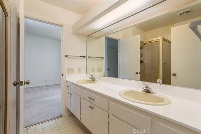 bathroom with tile patterned flooring, a shower with shower door, and vanity