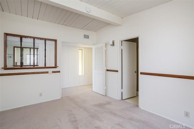 unfurnished room with beam ceiling and light colored carpet