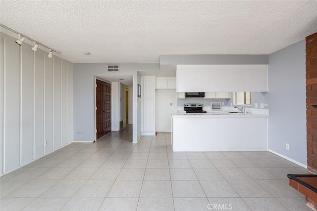 kitchen with a textured ceiling, white cabinets, kitchen peninsula, and electric stove