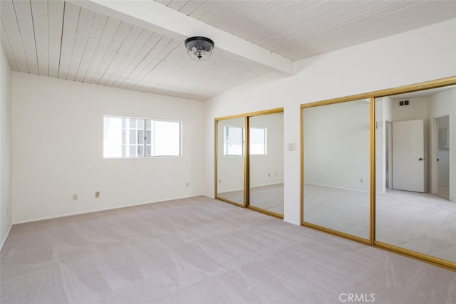 unfurnished bedroom featuring light colored carpet, lofted ceiling with beams, wood ceiling, and multiple closets