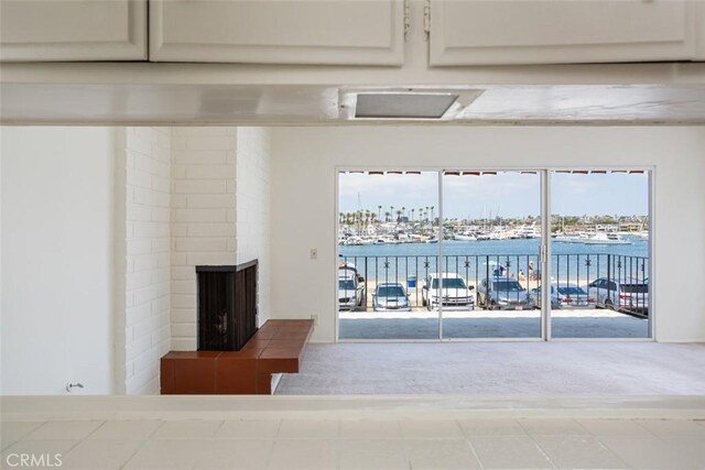 unfurnished living room featuring a water view, a fireplace, and carpet floors