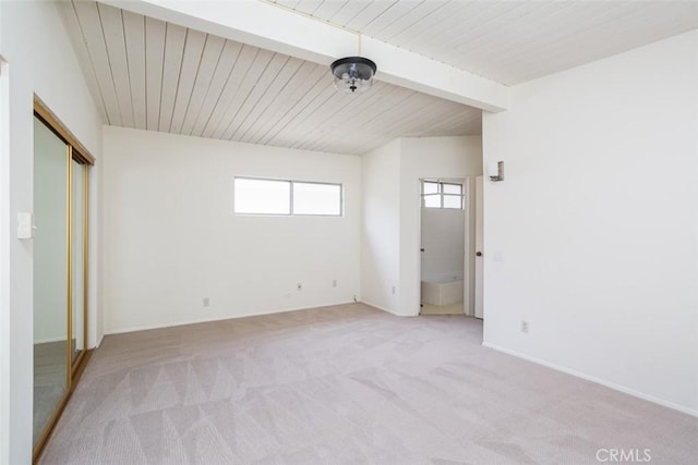 unfurnished bedroom with light colored carpet, a closet, and beam ceiling