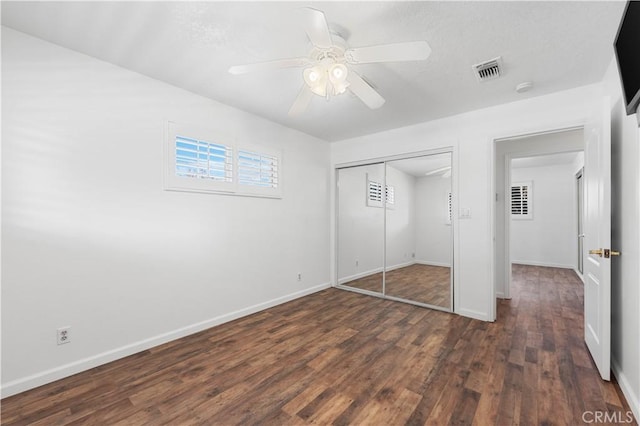 unfurnished bedroom with ceiling fan, a closet, and dark wood-type flooring