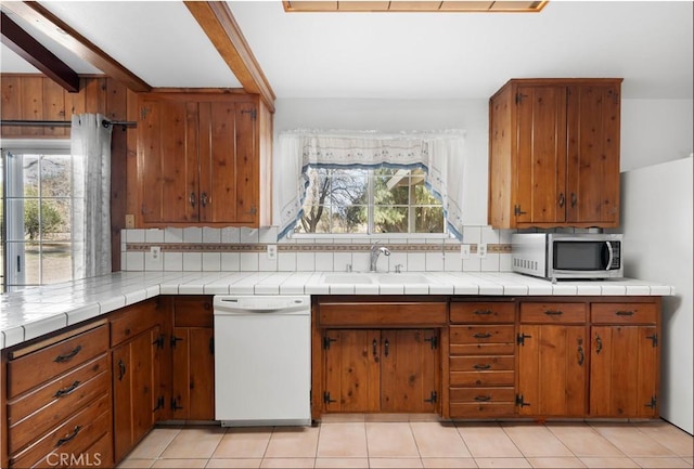 kitchen with tile counters, tasteful backsplash, white dishwasher, beam ceiling, and sink