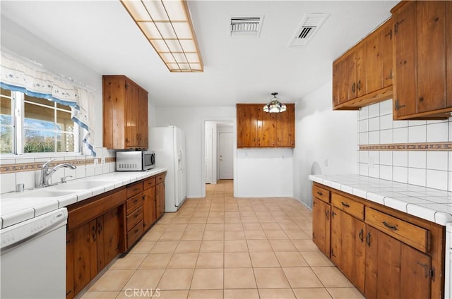 kitchen with sink, white appliances, tile counters, and tasteful backsplash