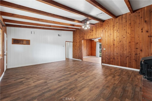 unfurnished living room featuring ceiling fan, beam ceiling, dark hardwood / wood-style floors, and wooden walls