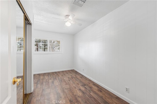 empty room featuring ceiling fan, dark hardwood / wood-style flooring, and a textured ceiling