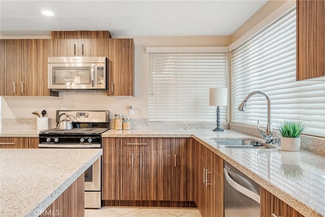 kitchen featuring sink, light stone counters, stainless steel appliances, and light tile patterned flooring