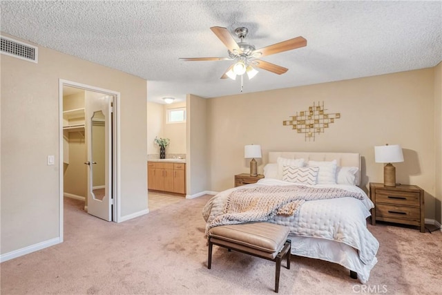 bedroom featuring ceiling fan, ensuite bath, a spacious closet, light carpet, and a closet