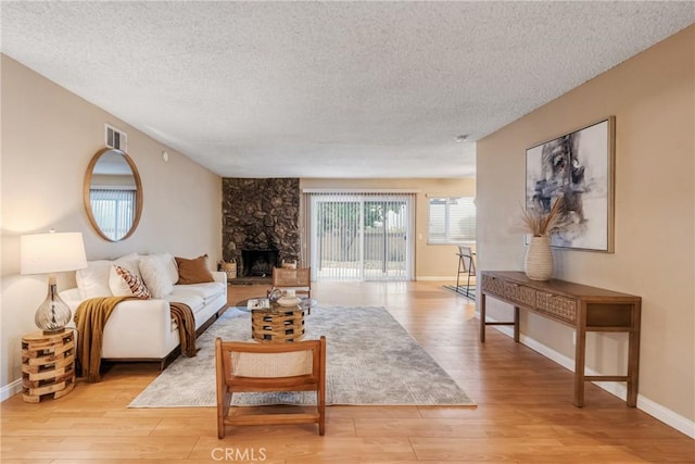 living room featuring a textured ceiling, a wood stove, and light hardwood / wood-style flooring