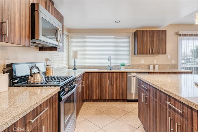 kitchen with light tile patterned floors, appliances with stainless steel finishes, sink, and light stone counters