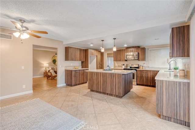 kitchen with stainless steel appliances, light tile patterned flooring, hanging light fixtures, a kitchen island, and sink