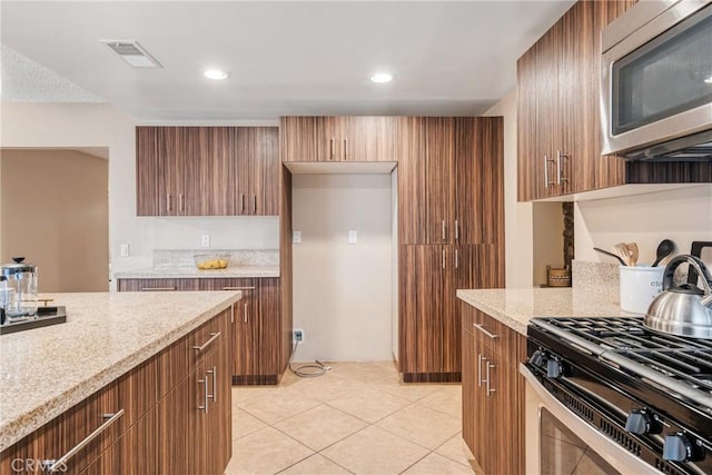 kitchen with light tile patterned floors, appliances with stainless steel finishes, and light stone countertops