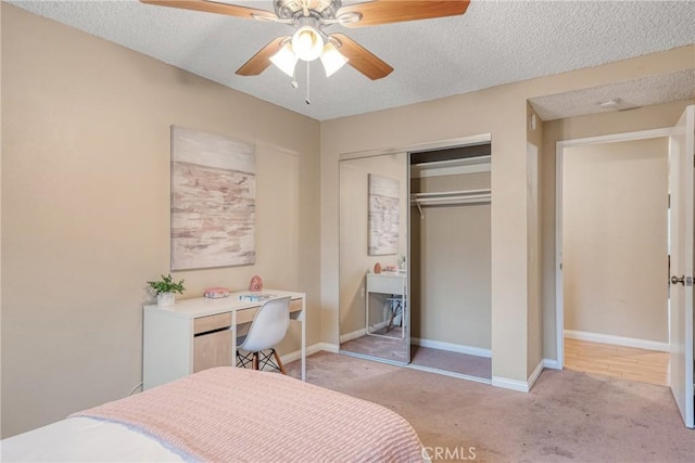 carpeted bedroom with ceiling fan, a closet, and a textured ceiling