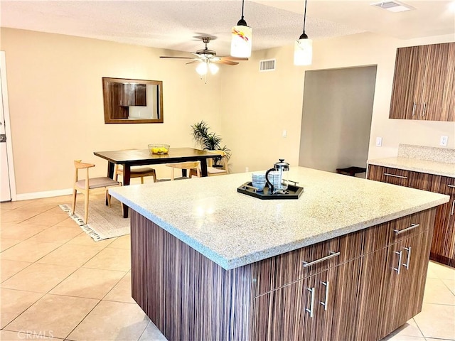 kitchen with pendant lighting, light tile patterned floors, a textured ceiling, and a kitchen island