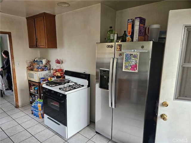 kitchen featuring stainless steel refrigerator with ice dispenser, light tile patterned floors, and gas stove