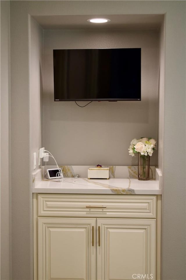 interior space with light stone countertops and cream cabinets