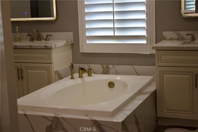 bathroom featuring tiled bath and vanity