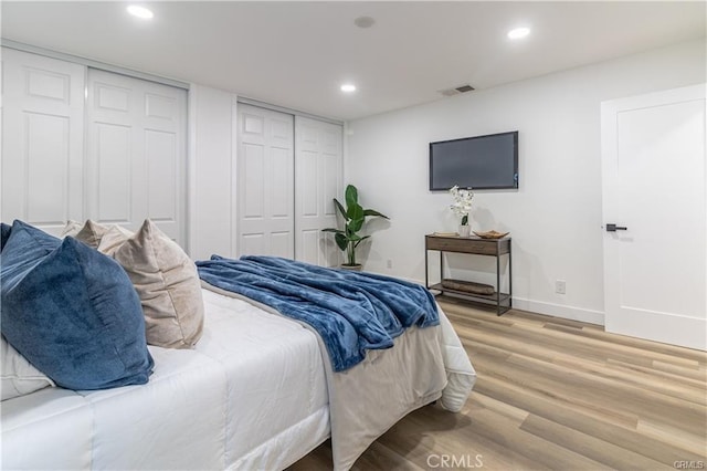 bedroom with light hardwood / wood-style flooring and multiple closets