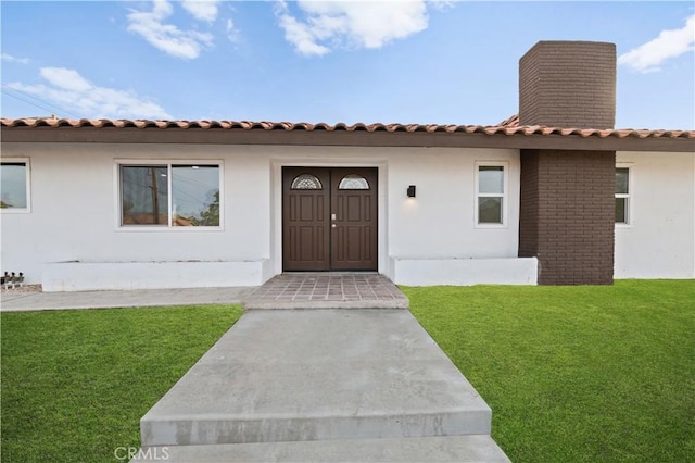 view of exterior entry featuring a yard