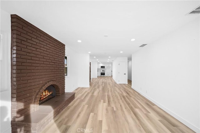 unfurnished living room with light hardwood / wood-style floors and a brick fireplace